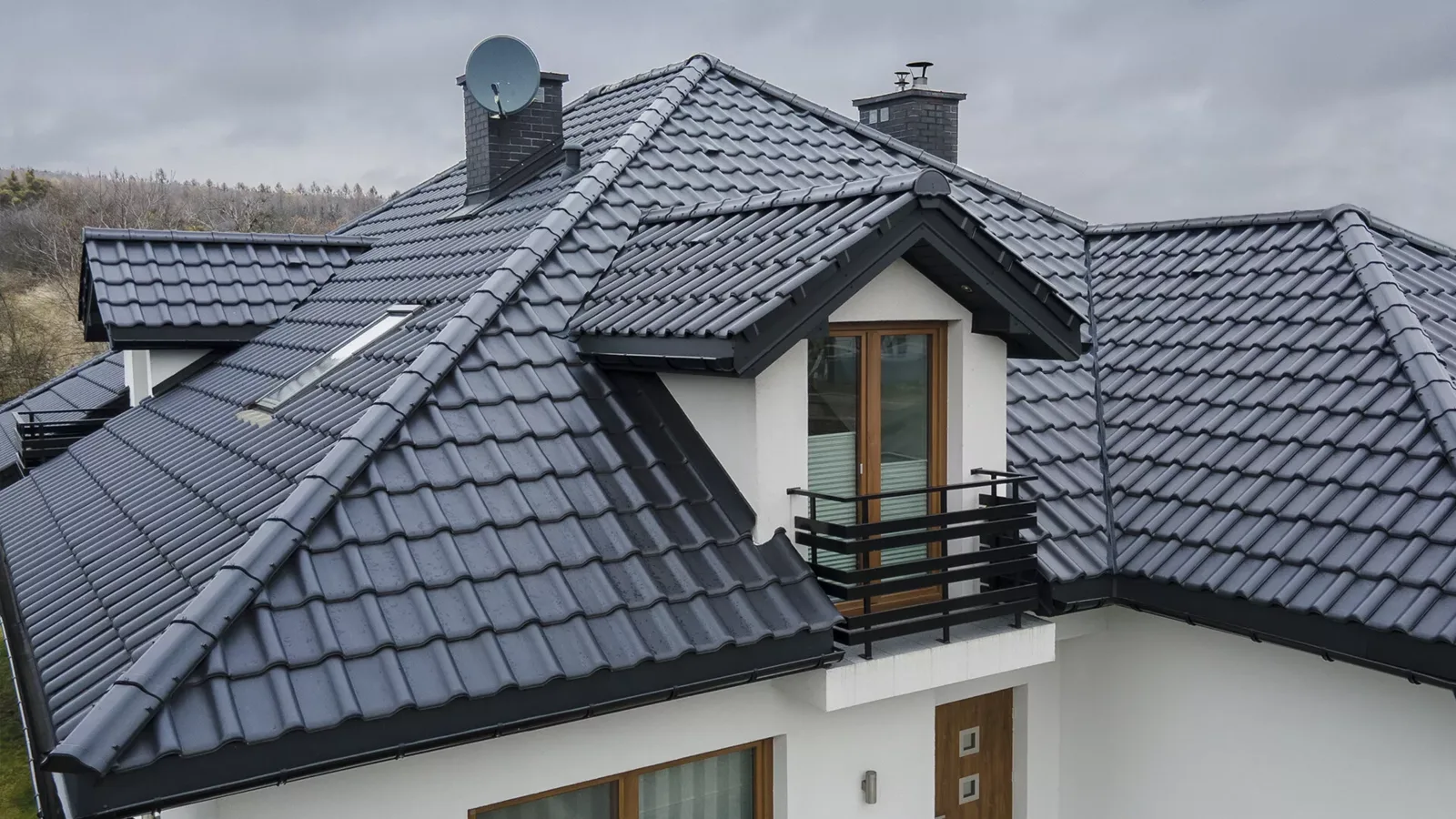 Wielospadowy dach domu jednorodzinnego kryty antracytową dachówką ceramiczną