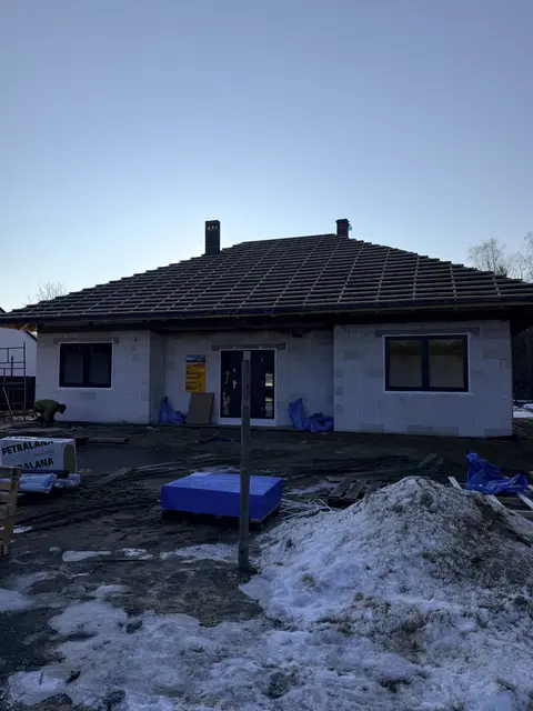 Dom parterowy z ciemnym dachem – realizacja zimowa