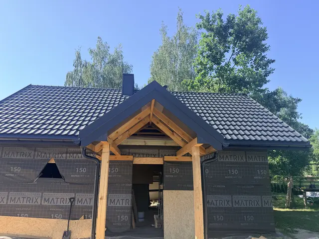 Dom z ciemną blachodachówką i drewnianym gankiem